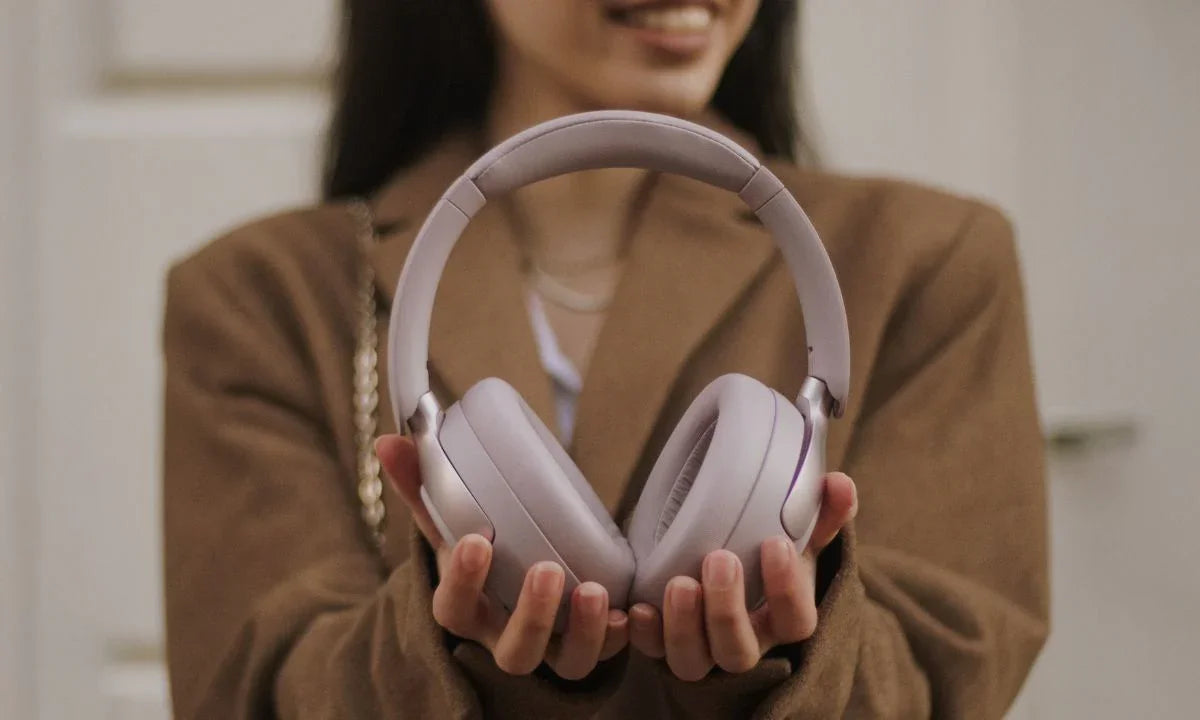 Woman holding light purple wireless over-ear headphones for immersive audio experience