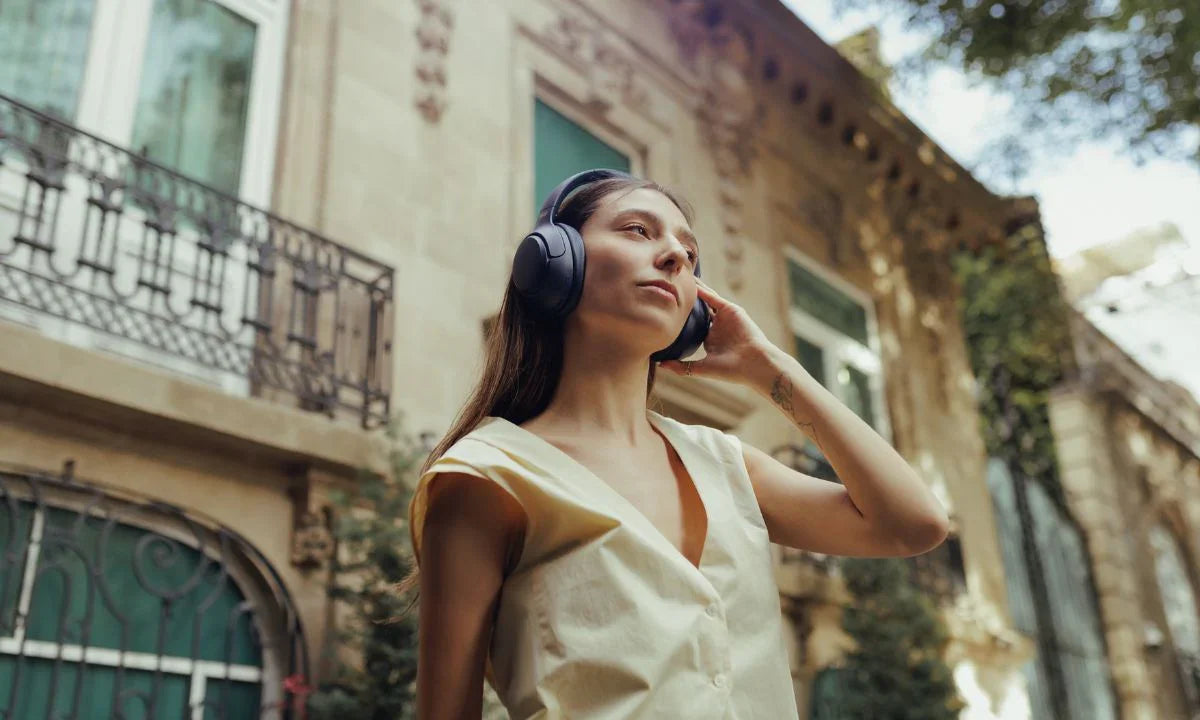 Woman wearing wireless headphones outdoors, enjoying immersive sound in urban setting