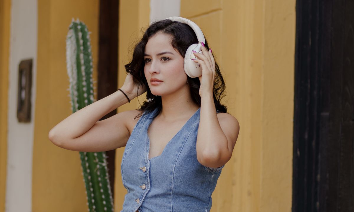 Woman wearing white wireless headphones outdoors near cactus, enjoying immersive sound