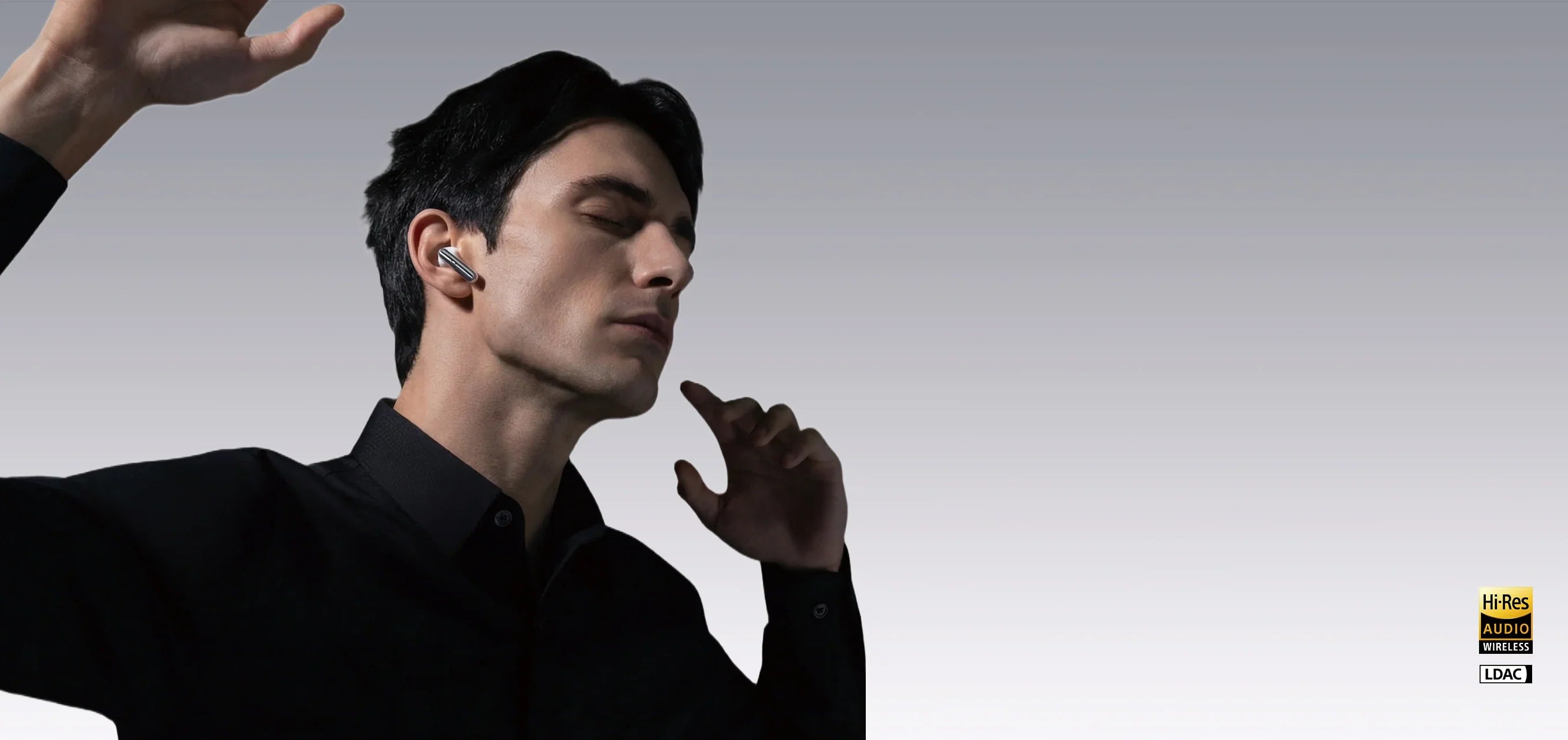 Man wearing wireless earbuds with one hand raised, illustrating potential volume imbalance issues.