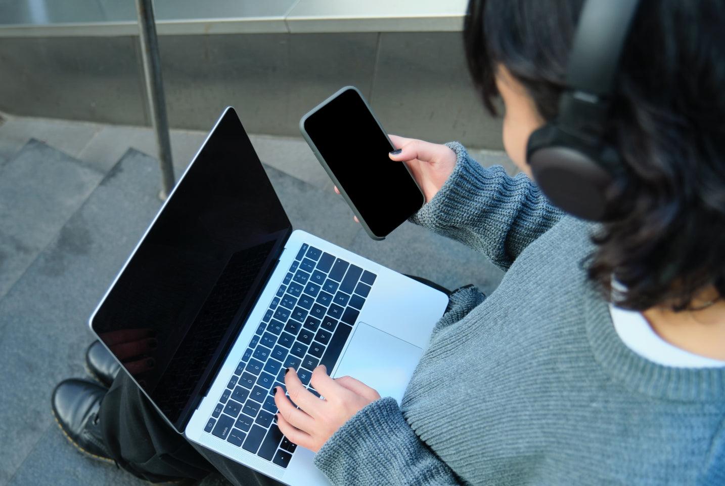 Person using wireless headphones with laptop and smartphone for immersive audio experience
