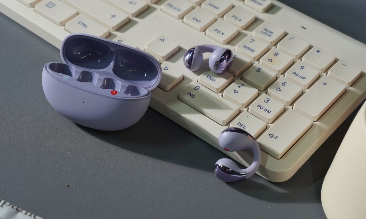 Purple wireless earbuds with charging case on vintage keyboard, ideal for iOS and Android