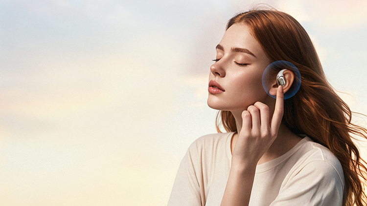 Woman wearing wireless earbuds enjoying music with eyes closed against soft sky background.