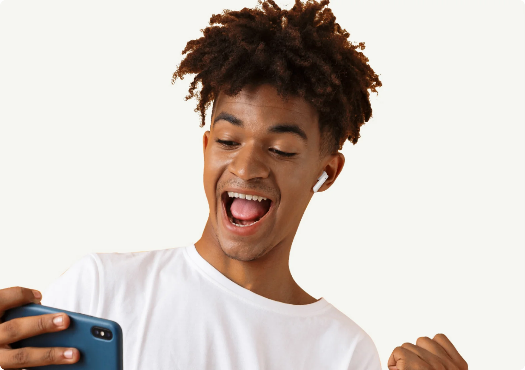 Happy young man with curly hair wearing white wireless earbuds, smiling while using a blue smartphone.