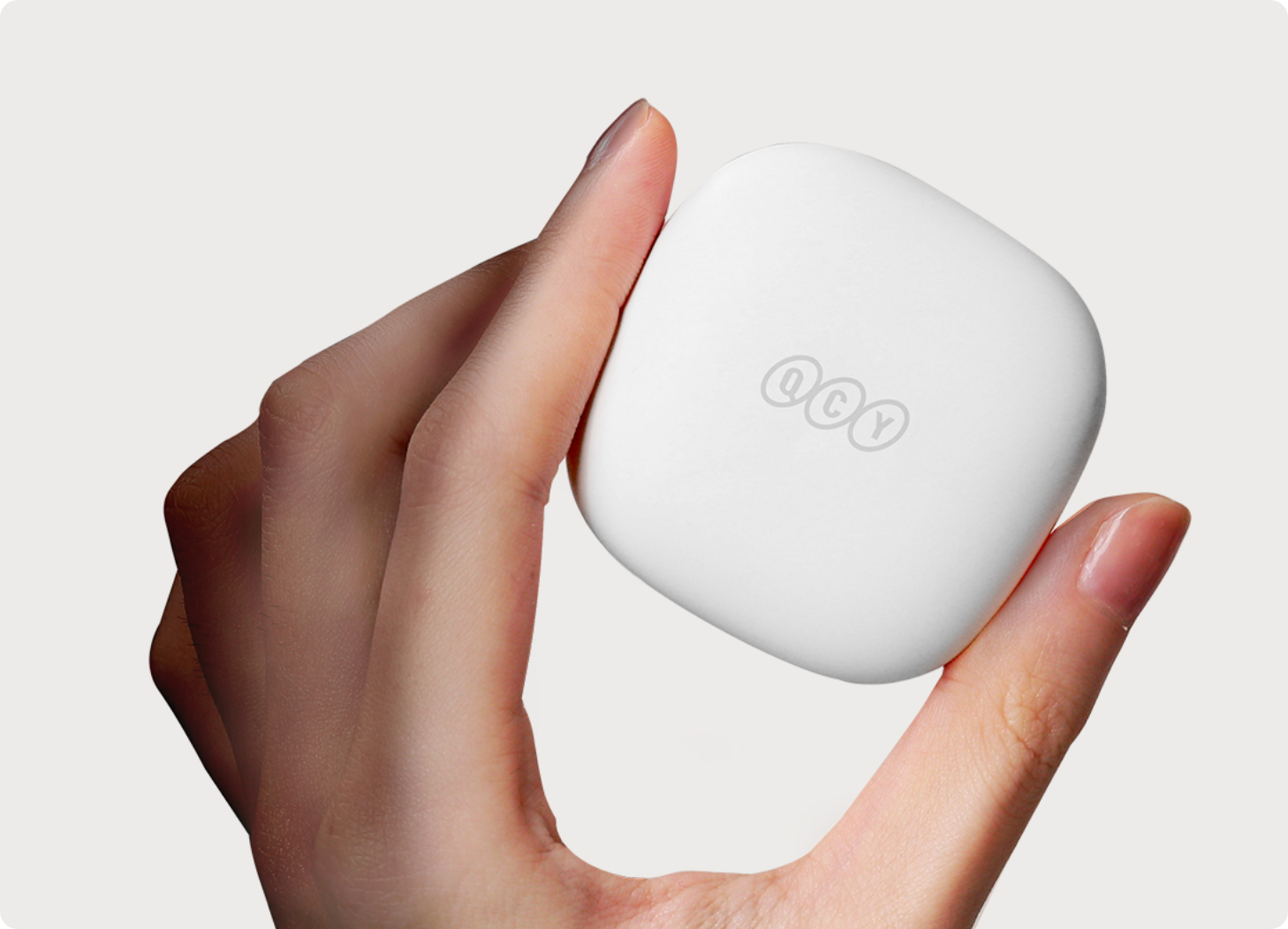 White QCY wireless earbuds charging case held in hand